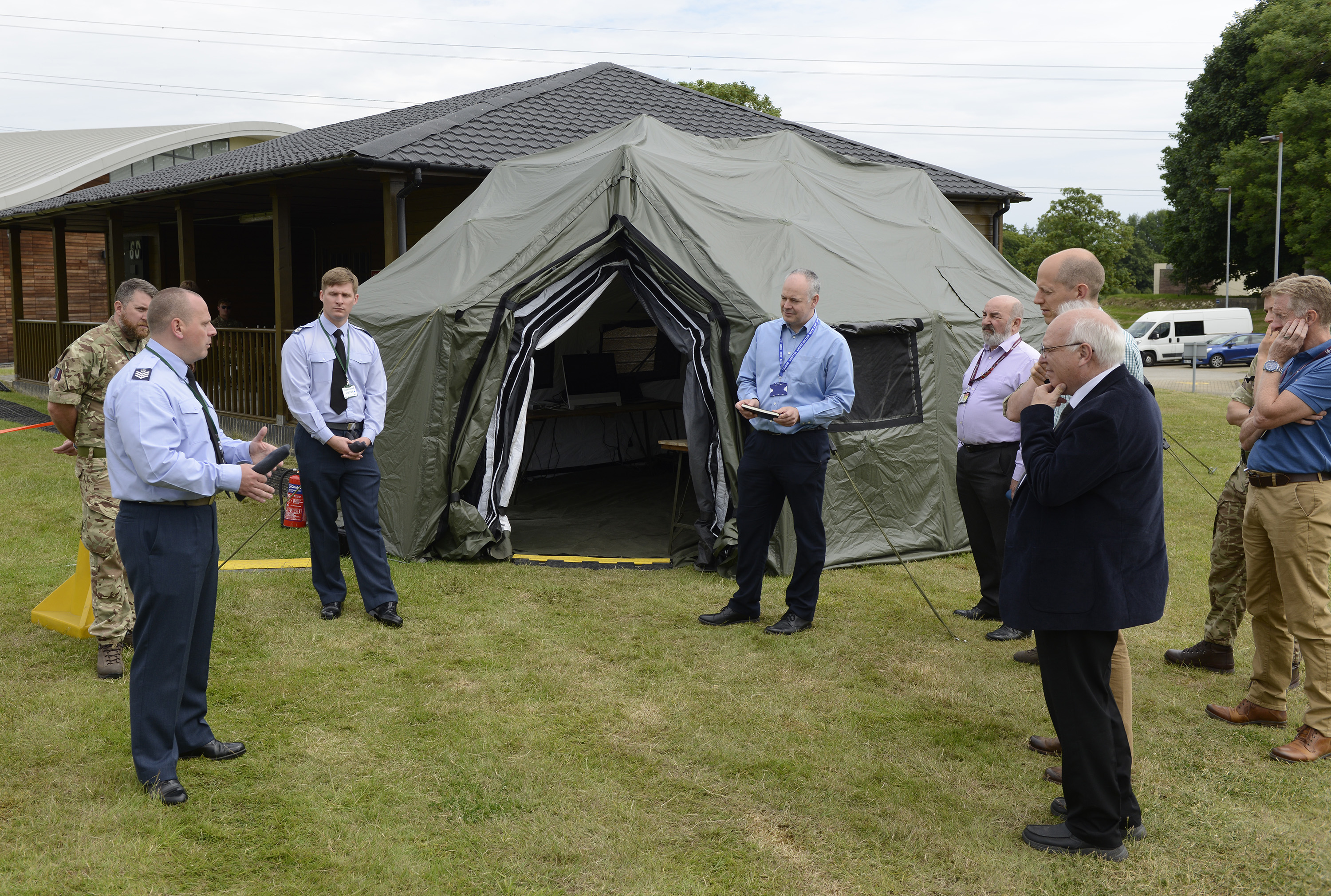 Image shows aviators and civilians outdoors by tent structure.